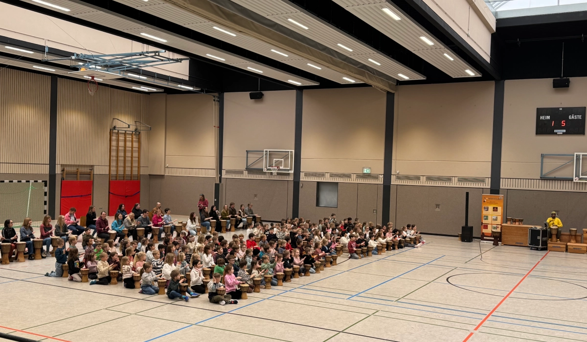 Kinder trommeln gemeinsam in der Turnhalle